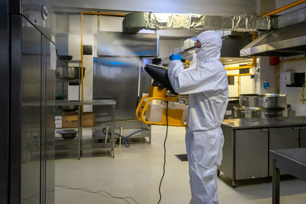A technician applying pest control in a commercial kitchen